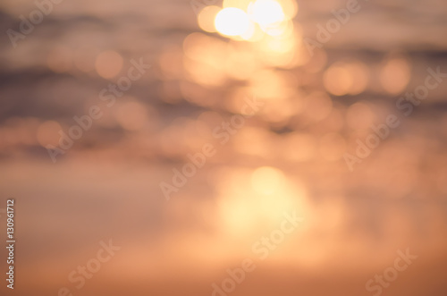 Blur tropical sunset beach with bokeh sun light wave abstract background.