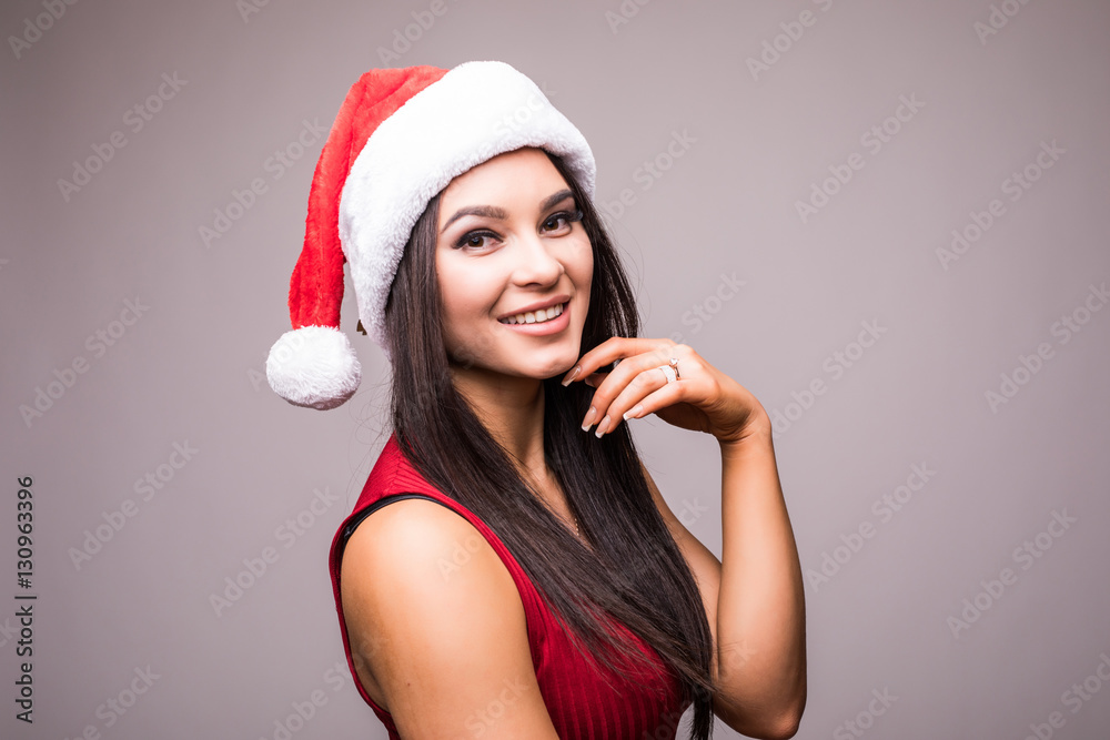 Portrait of beauty woman in red dress and Christmas santa hat over grey background
