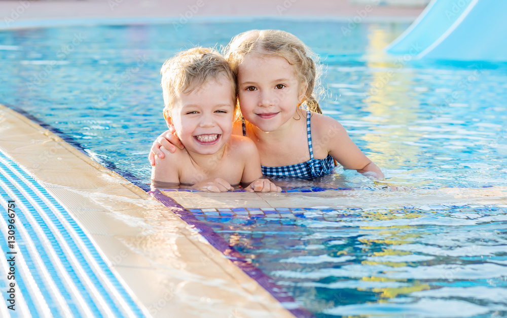 Happy young children in pool hugging