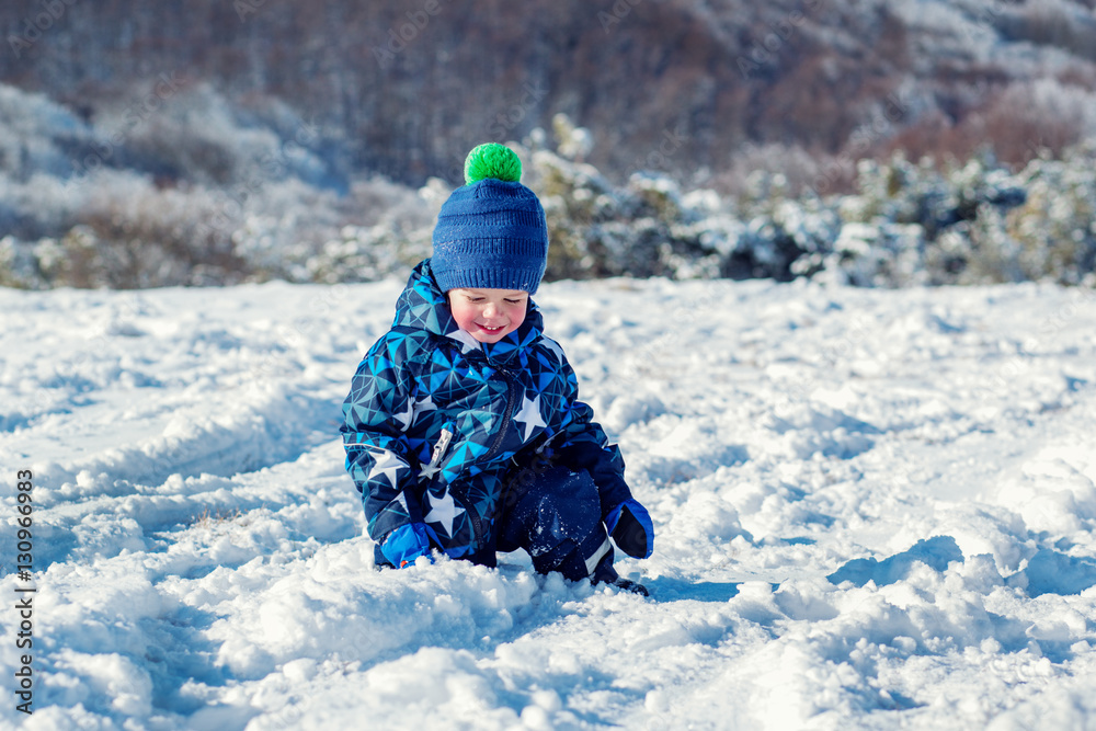 Cheeked happy toddler child touches the snow Cheeked happy toddler child touches the snow