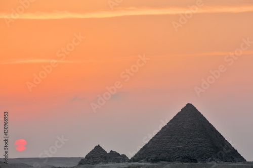 Dramatic sunset behind distant Egyptian pyramids in Giza  Cairo  Egypt  