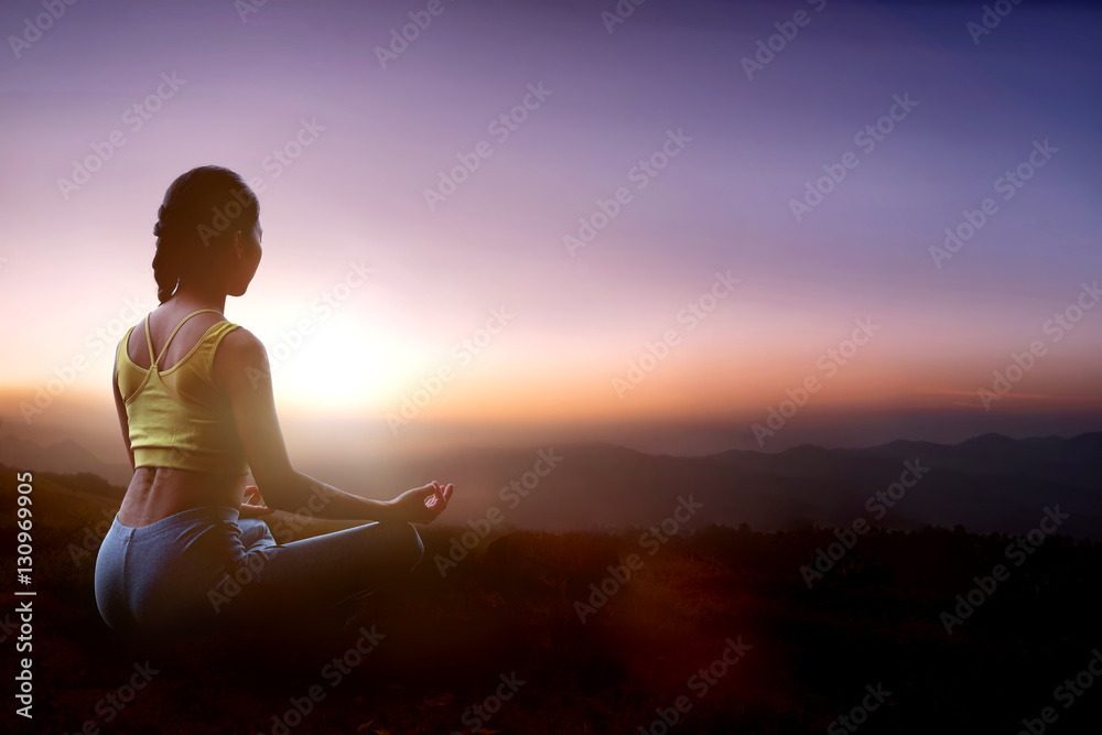 Young girl doing yoga at the mountain in the twilight.