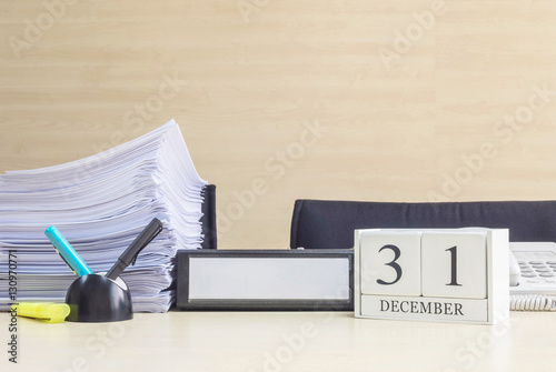 Closeup white wooden calendar with black 31 december word on blurred brown wood desk and wood wall textured background in office room view with copy space , selective focus at the calendar