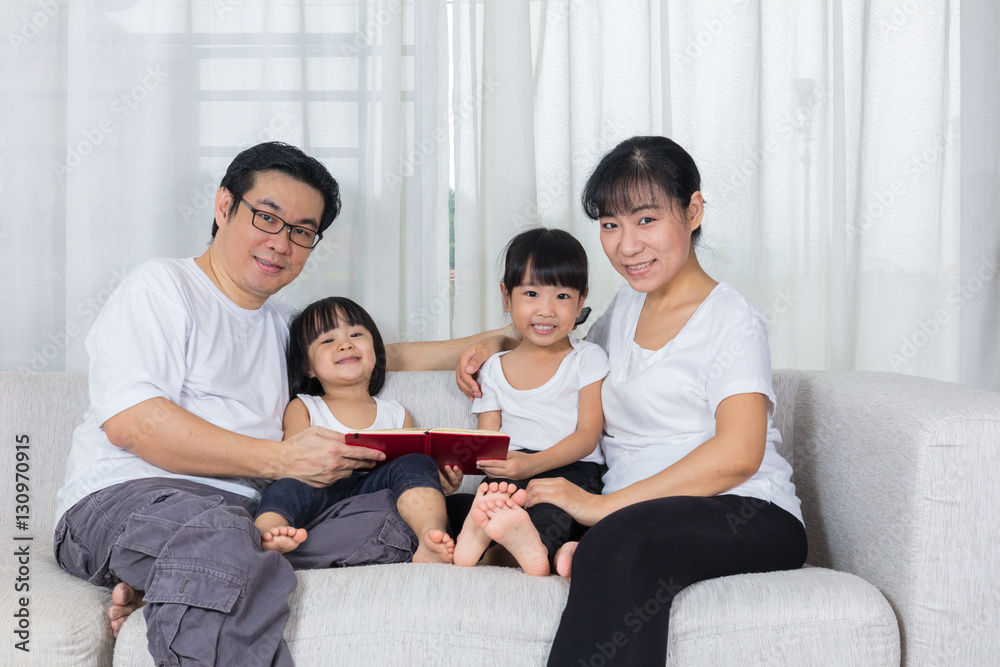 Happy Asian Chinese family reading book on the couch