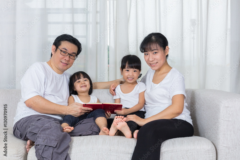 Happy Asian Chinese family reading book on the couch Happy Asian Chinese family reading book on the couch