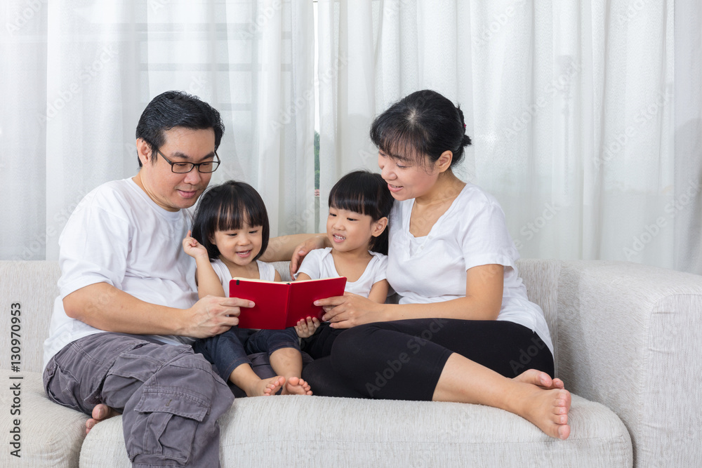 Happy Asian Chinese family reading book on the couch Happy Asian Chinese family reading book on the couch