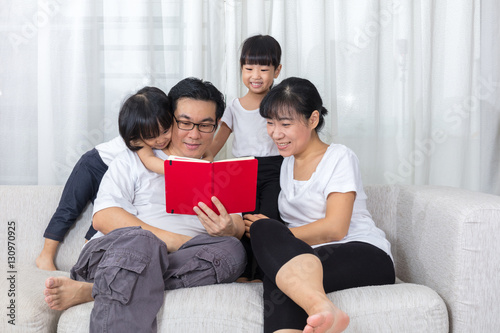 Happy Asian Chinese family reading book on the couch