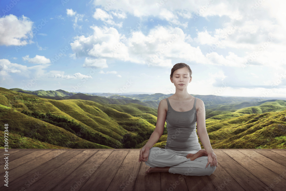 Young asian woman doing yoga lotus meditation on the wooden floor