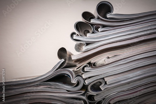 Several magazines opened and then stacked forming a pile with curls of paper