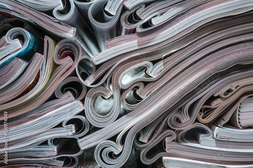 Several magazines opened and then stacked forming a pile with curls of paper