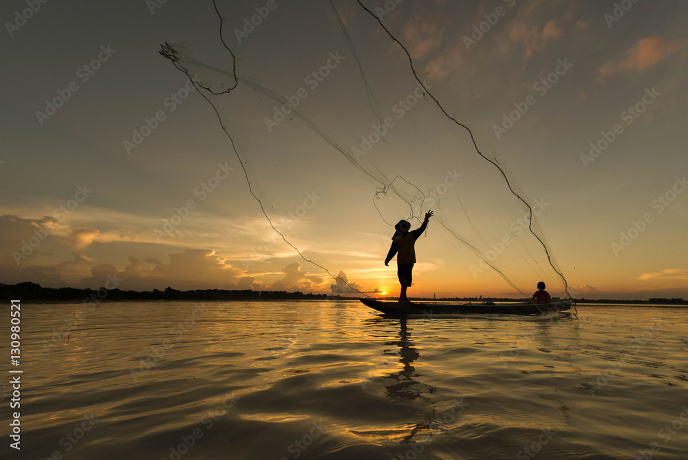 Silhouette of fisherman throwing net for fishing on the lake