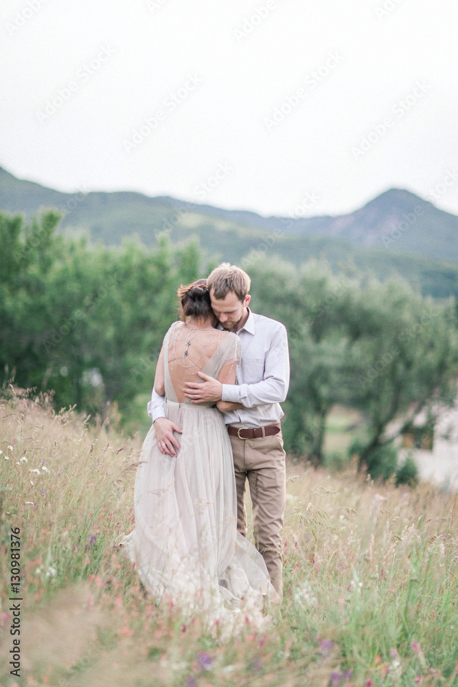 Couple in wedding attire with a bouquet of flowers and greenery