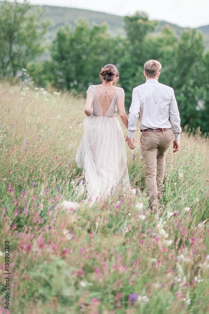 Couple in wedding attire with a bouquet of flowers and greenery
