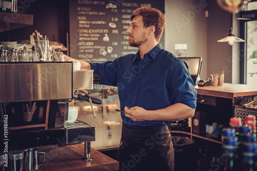 Handsome barista preparing cup of coffee for customer in coffee shop