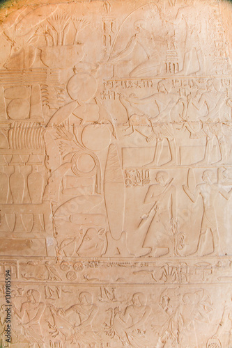 stone wall of egyptian temple with carved hieroglyphs, with ceremony procession of people with animals and food, in Egypt, Africa 
