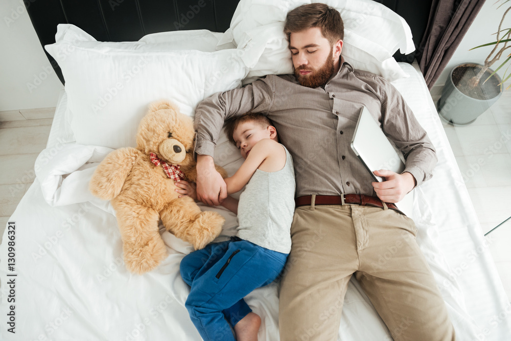 Little boy sleeping at home in bed with bearded father Little boy sleeping at home in bed with bearded father