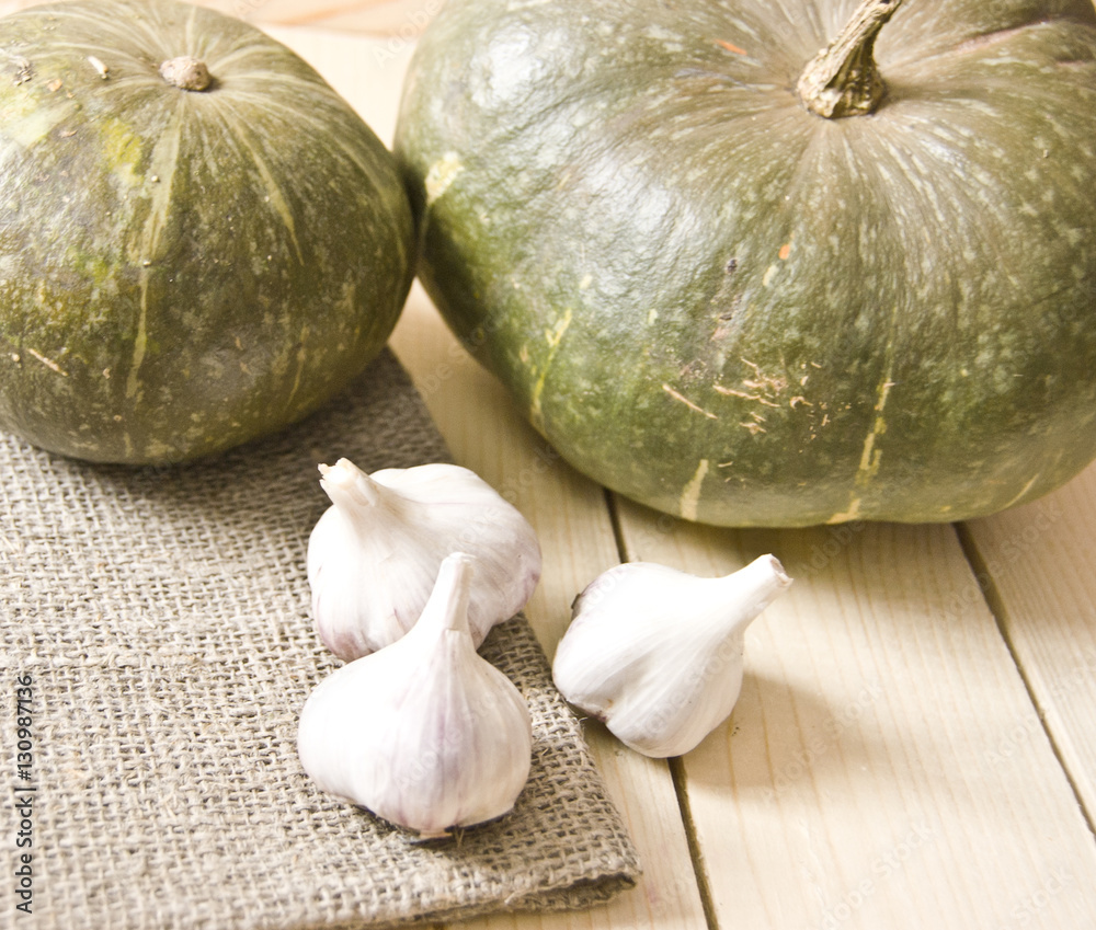Obraz premium fresh garlic and fresh pumpkin on a wooden table