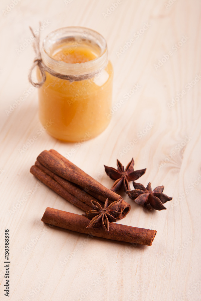 Honey in a glass jar and condiment cinnamon (Cinnamomum) and anise (Anisium vulgare Gaerto) lies on a light wood surface, background, close-up, a healthy lifestyle