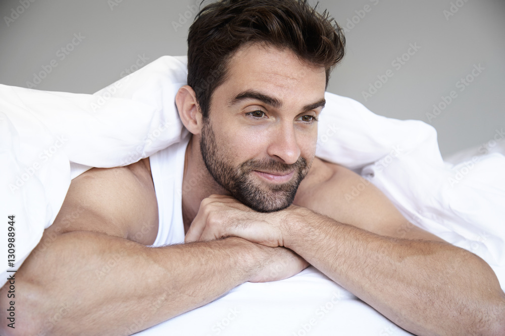 Obraz premium Man lying in bed under duvet