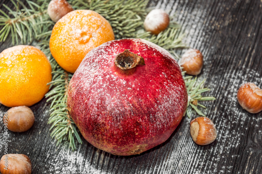 Pomegranate with tangerines, nuts and branch of christmas tree o