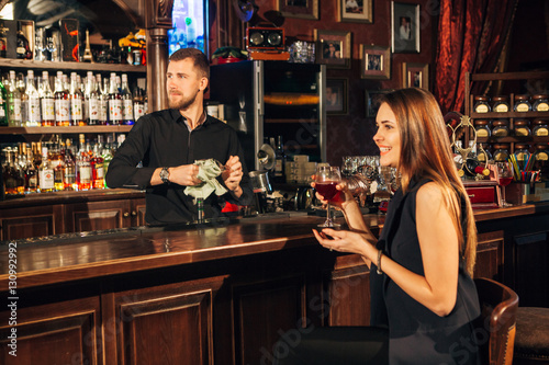 beautiful young woman sitting at the bar talking with the bartender