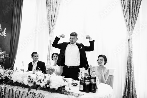 The groom stands near wedding table