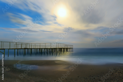 night view of the sea  the full moon illuminates the beach and pier. Slow shutter speed  