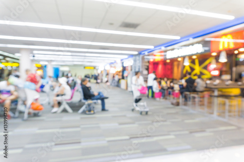 Defocused passenger in airport corridor with walking travelers