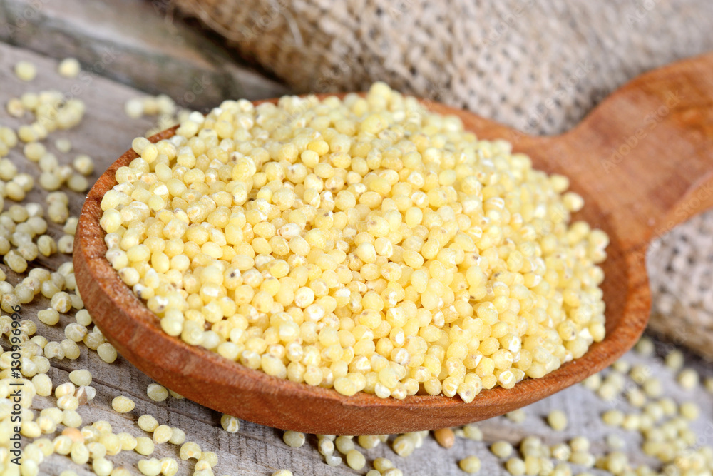 Millet seeds in a wooden spoon Millet seeds in a wooden spoon