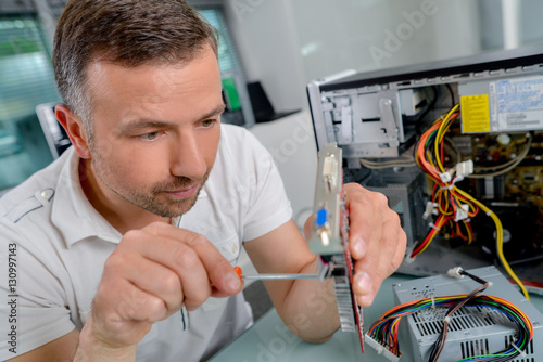 Man working on computer using screwdriver