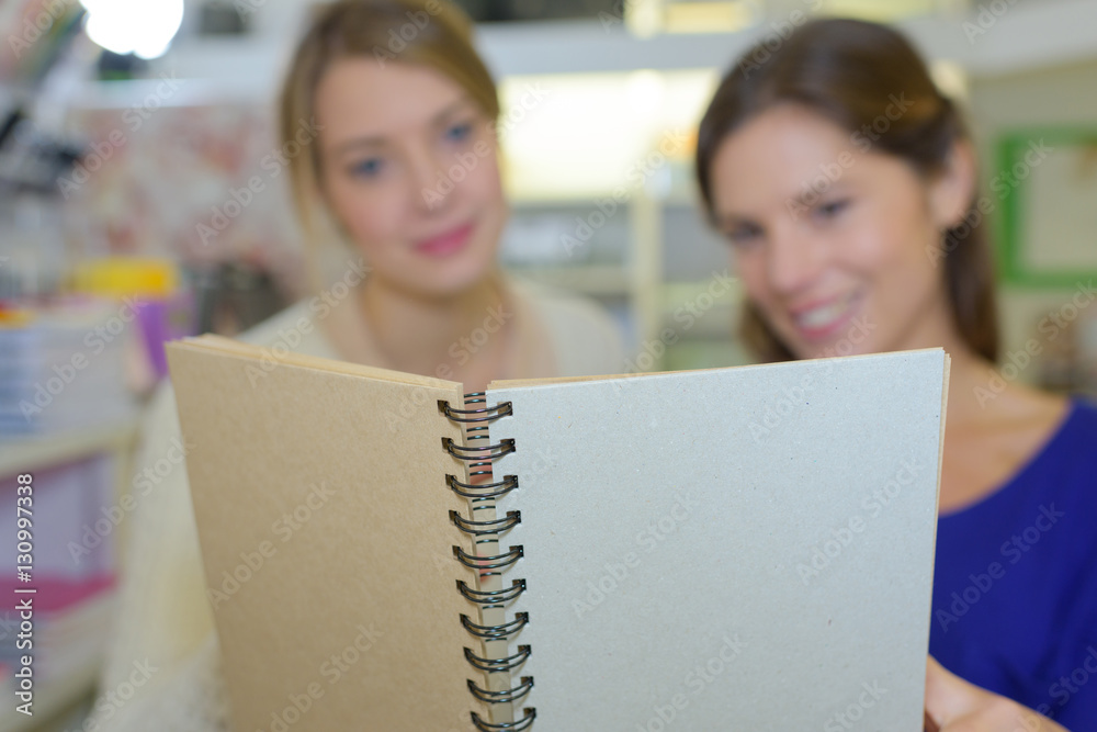friends reading shopping list in notebook friends reading shopping list in notebook