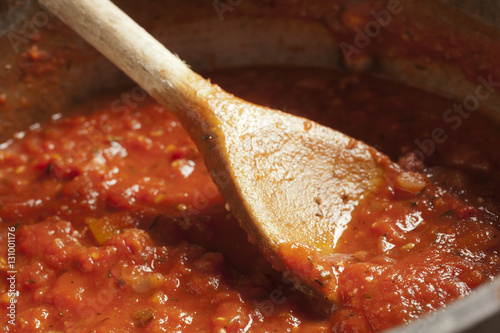 A pot of tomato sauce with a wooden spoon