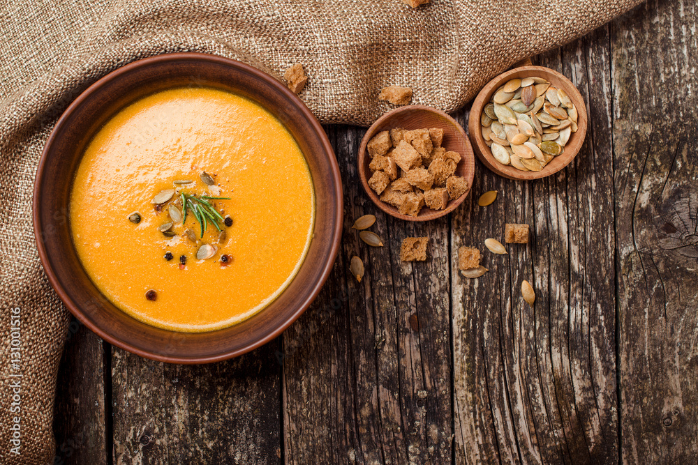 Bowl of pumpkin soup with bread crouton on dark wooden table. Bowl of pumpkin soup with bread crouton on dark wooden table.
