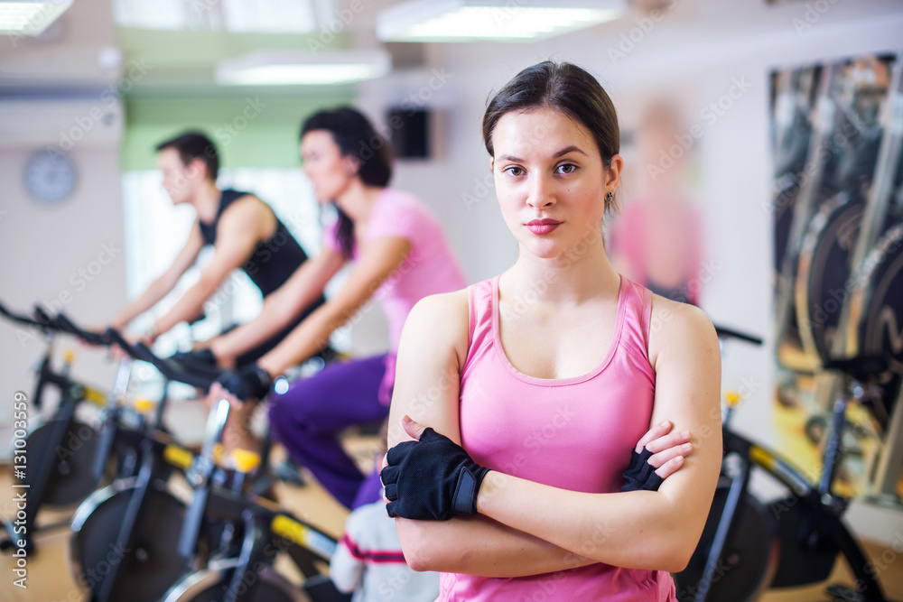 Group training people biking in the gym, exercising legs doing cardio workout cycling bikes