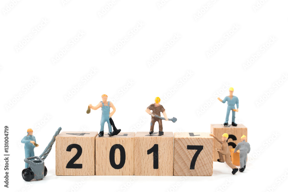 Miniature worker team building wooden block number 2017 on white background