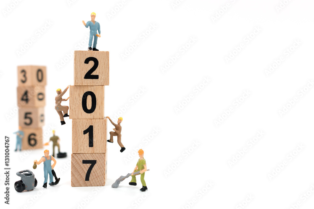 Miniature worker team building wooden block number 2017 on white background Miniature worker team building wooden block number 2017 on white background