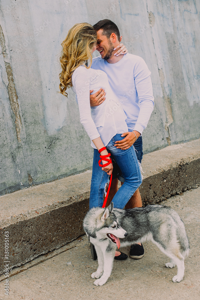 Beautiful young couple playing with a dog husky in a park. Summe Beautiful young couple playing with a dog husky in a park. Summe