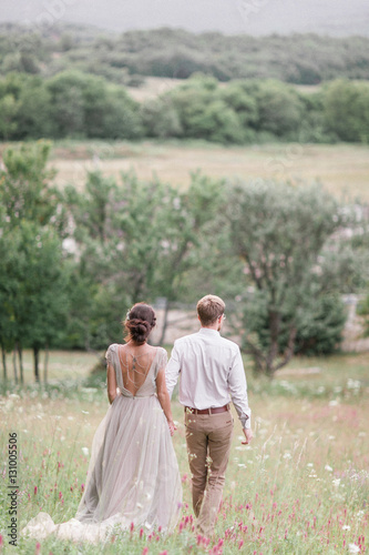 Couple in wedding attire with a bouquet of flowers and greenery