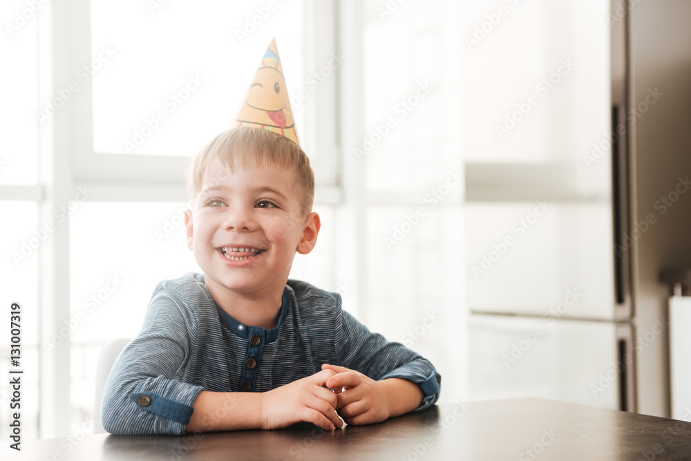 Cheerful birthday boy sitting in kitchen while smiling Cheerful birthday boy sitting in kitchen while smiling