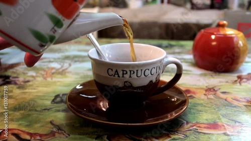 pouring tea into a cup.