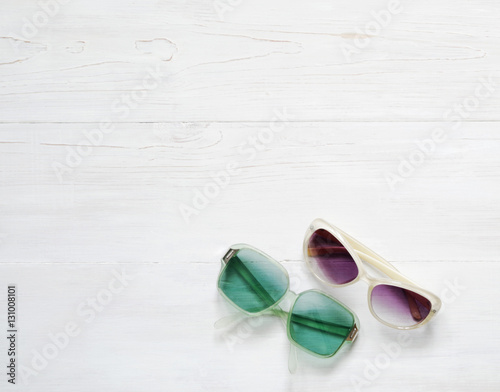 Pair of old women's and men's fashioned sunglasses on wooden white floor background, top view. Place for text.