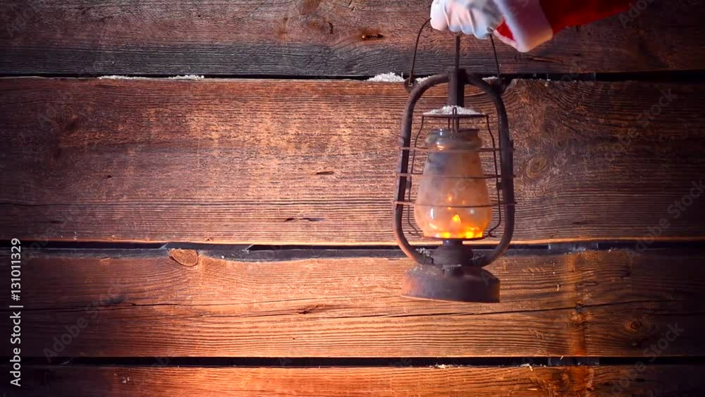Santa's hand holding vintage oil lamp over Christmas holiday wooden background. Full HD 1080p video footage