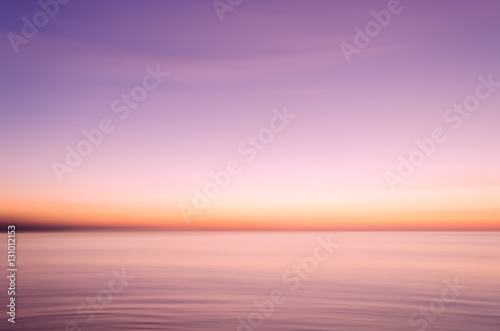 Motion blur tropical sunset beach with bokeh sun light wave abstract background.