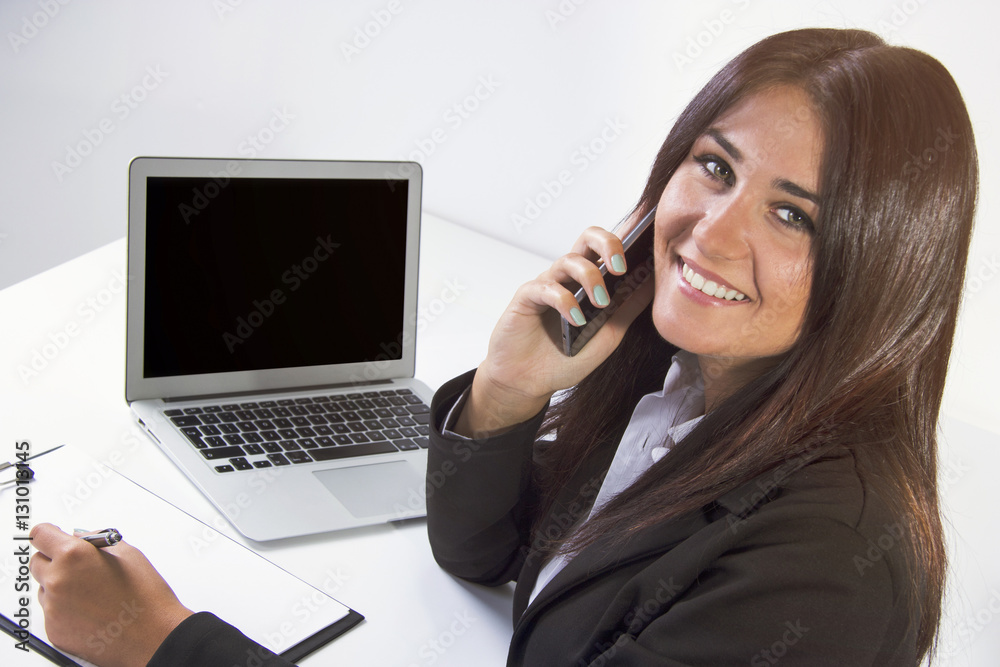 Business woman making a phone call while smiling and looking at the camera.