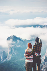Happy Couple Man and Woman hugging enjoying mountains and clouds landscape on background Love and Travel emotions Lifestyle concept. Young family traveling active adventure vacations. rear view