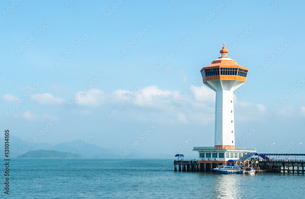 Big White and Orange Lighthouse with Boat at The Corner and Blue Sea and Sky in Background as Copyspace to input Text