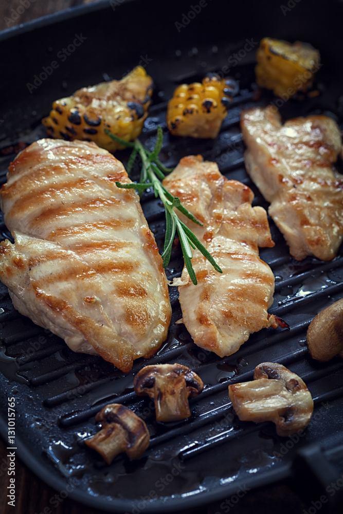 Grilled chicken breast with mushroom and rosemary on a wooden board or grill pan Grilled chicken breast with mushroom and rosemary on a wooden board or grill pan