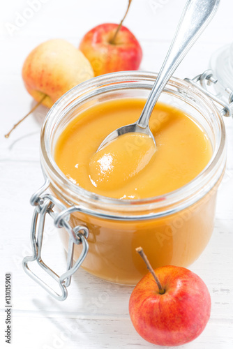 fresh apple sauce in a glass jar, vertical closeup photo