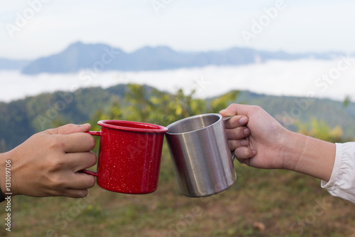 Cheers lass of two people make a toast at the mountain top view from their camping site with red and silver glass photo