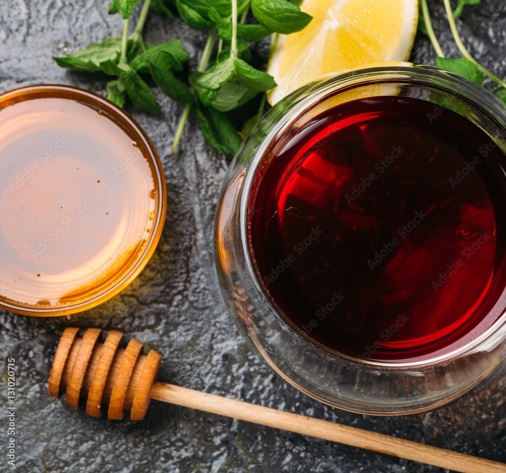 Food background with cup of tea, honey, lemon and mint on black table Top view Food background with cup of tea, honey, lemon and mint on black table Top view